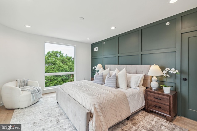bedroom featuring a decorative wall, recessed lighting, and light wood finished floors