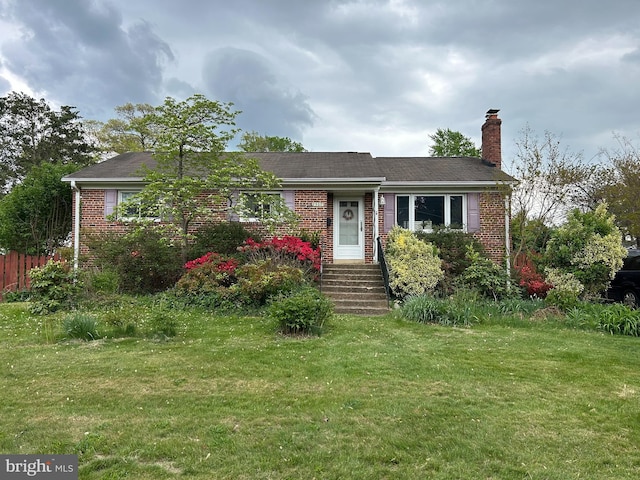 ranch-style house featuring brick siding, a front yard, and a chimney