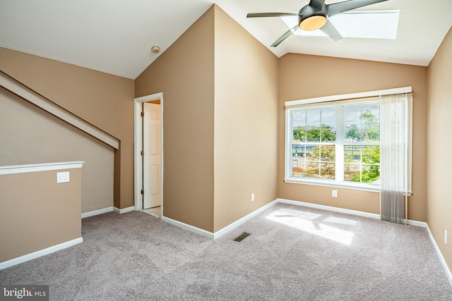 carpeted spare room featuring vaulted ceiling, visible vents, baseboards, and a ceiling fan