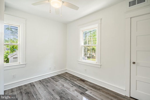 spare room with a wealth of natural light, visible vents, and wood finished floors