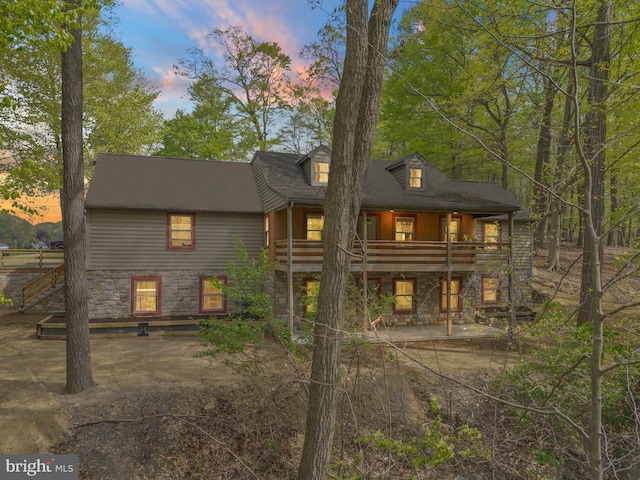 rear view of property featuring a patio area, a balcony, and stone siding