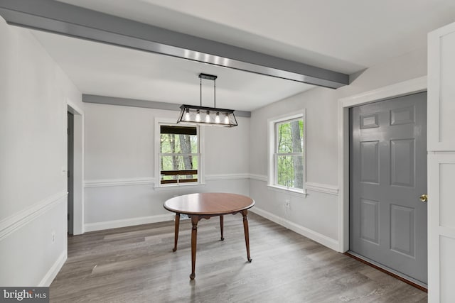 dining space with baseboards, beam ceiling, and wood finished floors