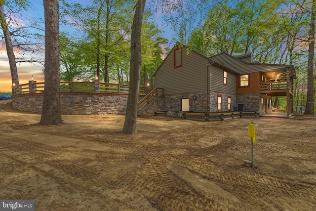 property exterior at dusk with stairs and stone siding