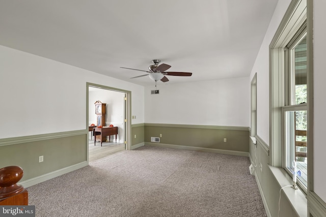 empty room with visible vents, a ceiling fan, baseboards, and carpet flooring