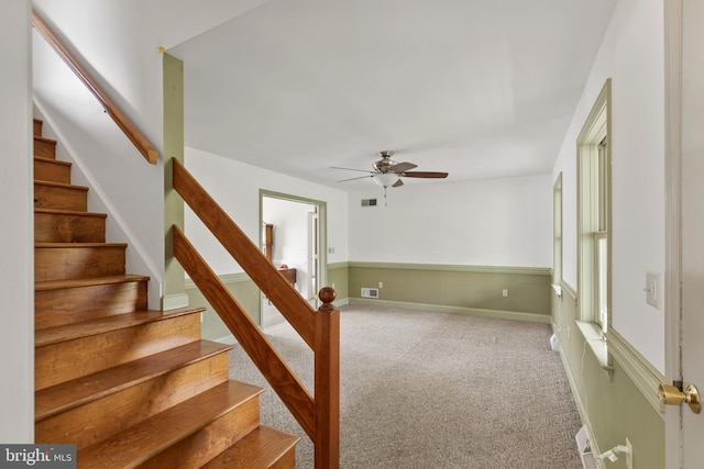stairway with carpet floors, a ceiling fan, baseboards, and visible vents