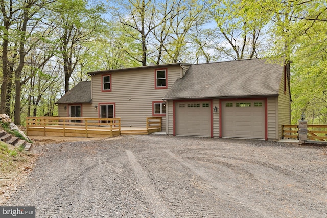 view of front of property featuring a wooden deck, roof with shingles, and a garage