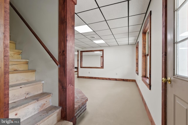 basement with stairway, baseboards, and a paneled ceiling