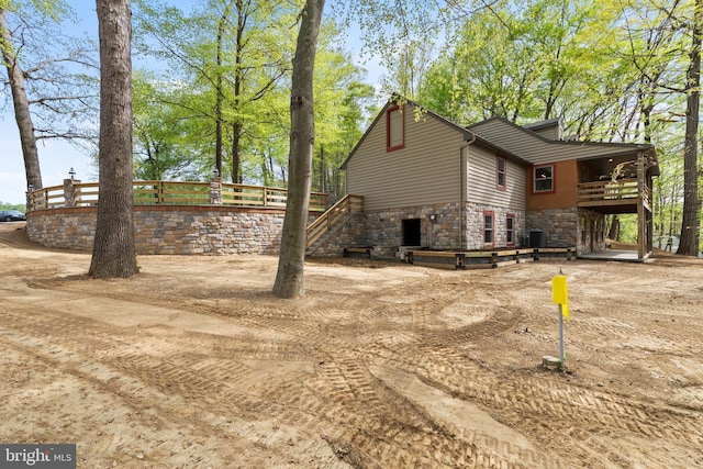 view of side of property with stairs and stone siding