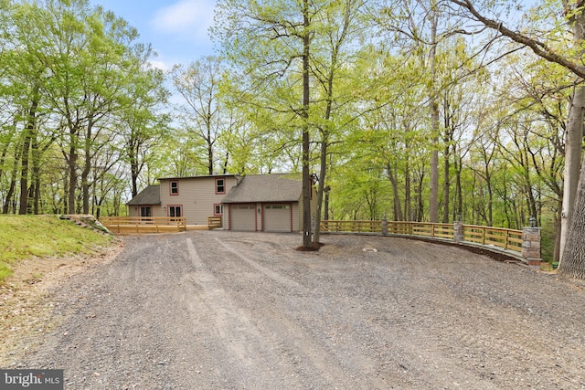 view of front facade with fence, a wooden deck, roof with shingles, and dirt driveway