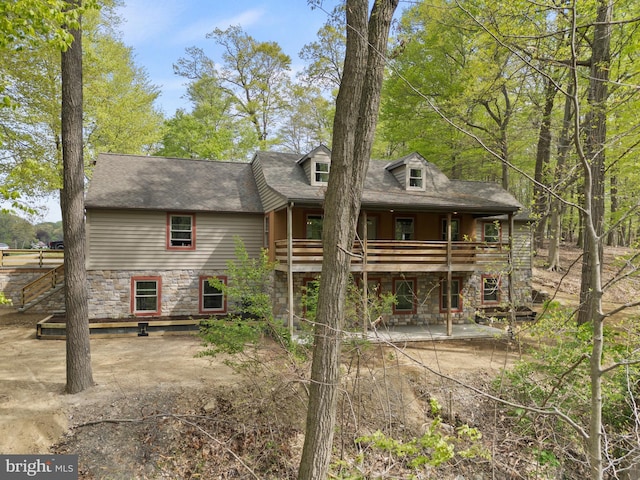 rear view of house with a patio and stone siding