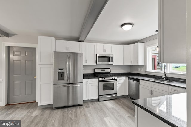 kitchen with white cabinets, stainless steel appliances, beamed ceiling, and a sink