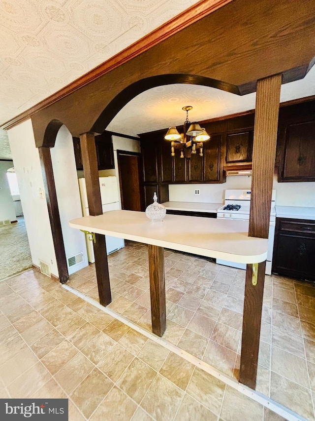 2633 Levick St, Philadelphia, PA 19149 - kitchen with arched walkways, dark brown cabinets, a notable chandelier, white appliances, and light countertops