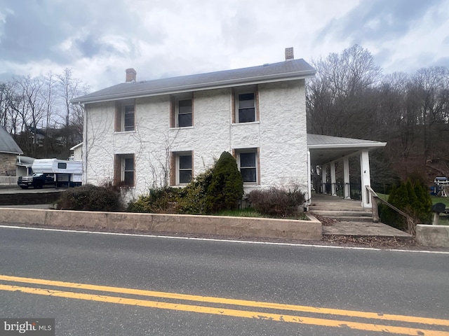 colonial house featuring a porch and a chimney