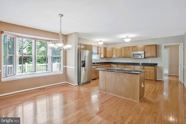kitchen with baseboards, light wood finished floors, an inviting chandelier, dark countertops, and stainless steel appliances