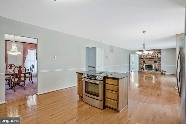 kitchen featuring light wood-style flooring, open floor plan, a chandelier, dark countertops, and appliances with stainless steel finishes