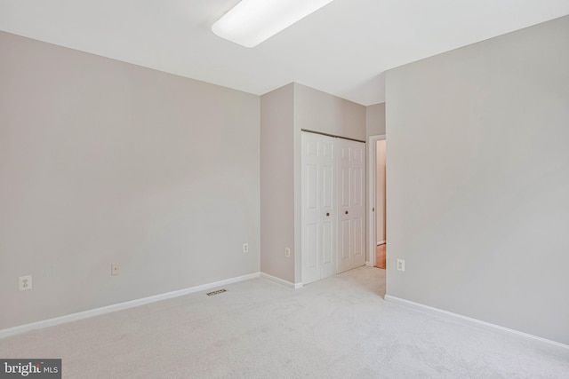 unfurnished bedroom with light colored carpet, a closet, visible vents, and baseboards