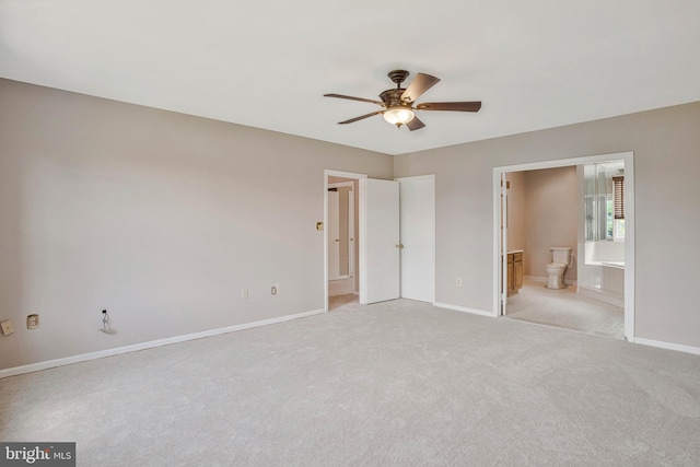 unfurnished bedroom with ensuite bathroom, light carpet, baseboards, and a ceiling fan