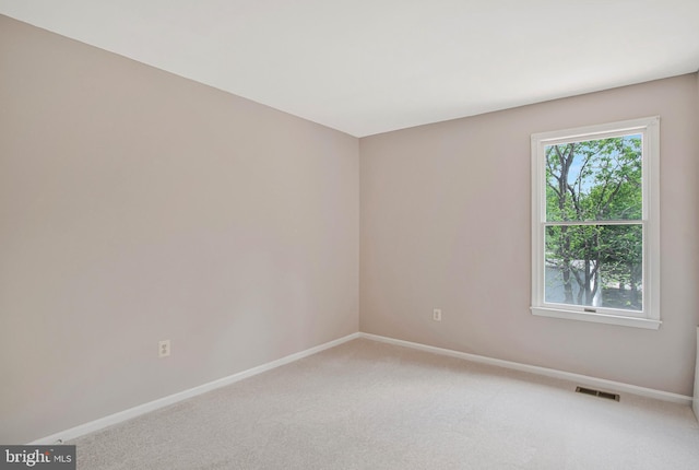 spare room featuring baseboards, visible vents, and light colored carpet