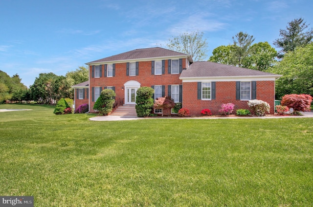 colonial home with brick siding and a front lawn