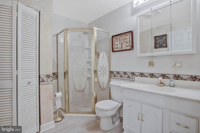 bathroom with toilet, a closet, vanity, and a stall shower