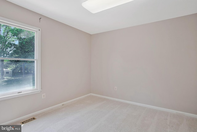 spare room with baseboards, light carpet, and visible vents