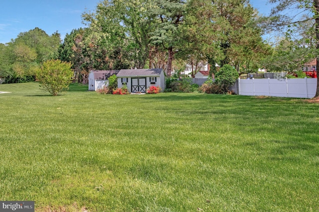 view of yard with fence, a storage shed, and an outdoor structure