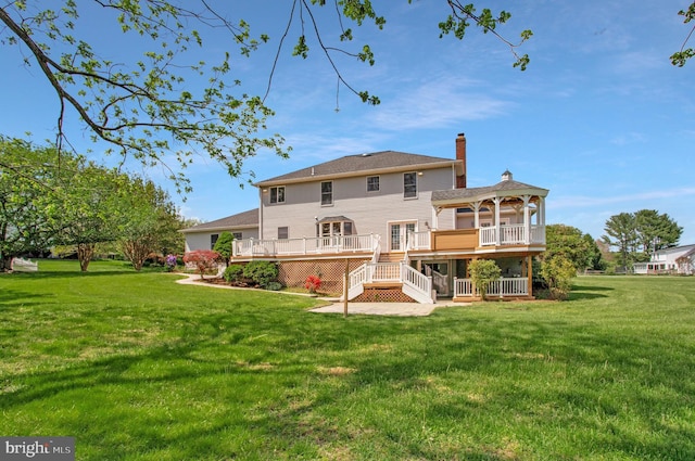 back of property with a gazebo, a deck, a chimney, and a lawn