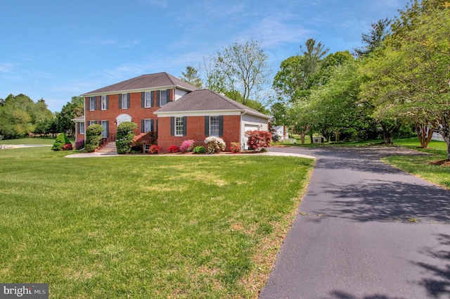 colonial-style house with a front yard, a garage, brick siding, and driveway