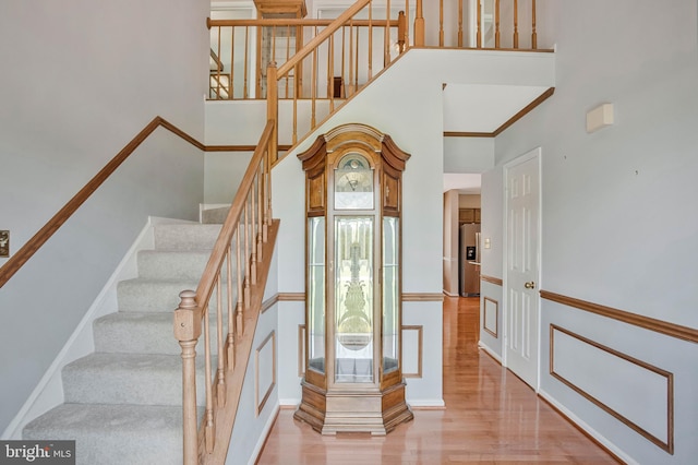 stairs featuring a towering ceiling and wood finished floors