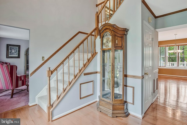 staircase with baseboards, a notable chandelier, and wood finished floors