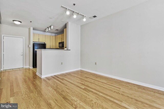 unfurnished living room featuring visible vents, rail lighting, light wood-style flooring, and baseboards