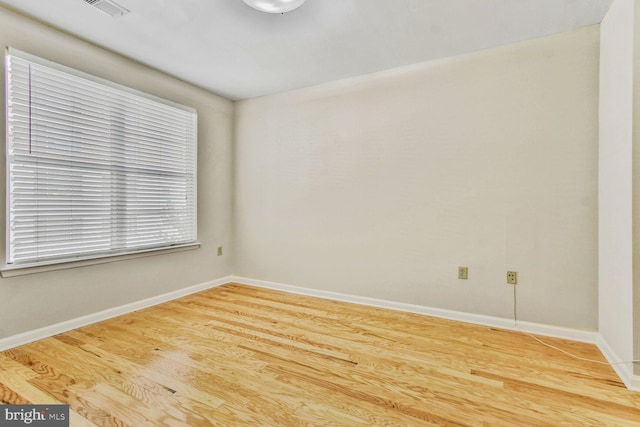 unfurnished room featuring wood finished floors, visible vents, and baseboards