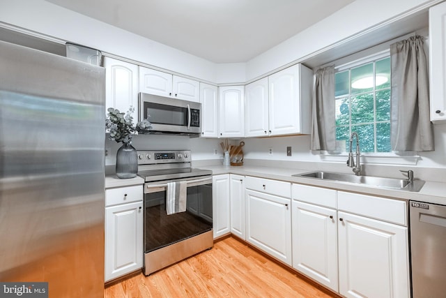 1541 Church Hill Pl Unit 1541, Reston, VA 20194 - kitchen featuring stainless steel appliances, a sink, white cabinetry, light countertops, and light wood-type flooring