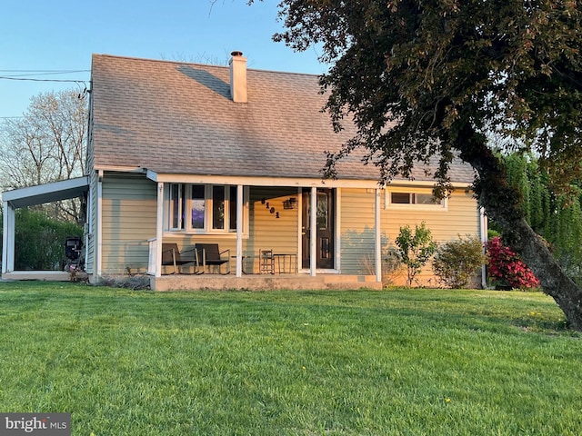 back of property featuring a lawn, a porch, a chimney, and roof with shingles