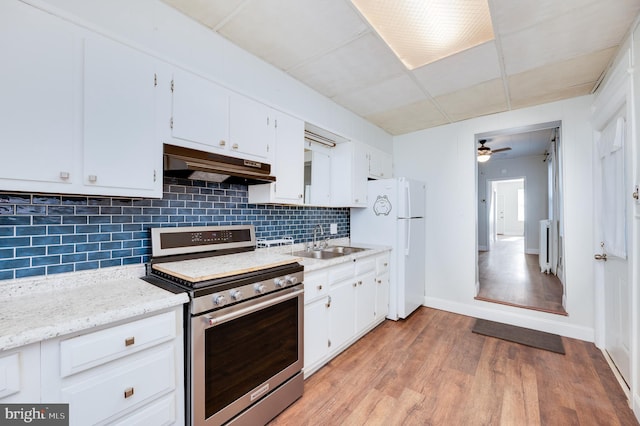kitchen with a sink, freestanding refrigerator, backsplash, stainless steel gas stove, and under cabinet range hood