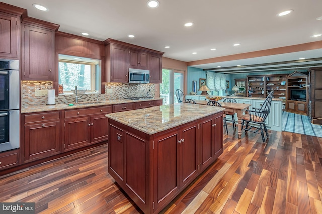 kitchen with dark wood-style floors, a sink, decorative backsplash, a healthy amount of sunlight, and appliances with stainless steel finishes