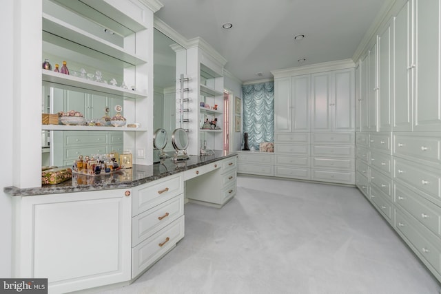 spacious closet featuring built in study area and light colored carpet
