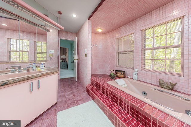 full bathroom with tile walls, vanity, a whirlpool tub, tile patterned floors, and a tile shower