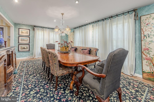 dining space with baseboards, wood finished floors, and a notable chandelier