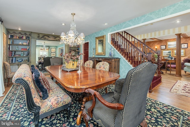 dining space with stairs, a notable chandelier, wallpapered walls, and wood finished floors