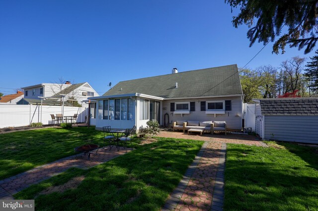 rear view of property with an outdoor living space with a fire pit, fence, an outdoor structure, a sunroom, and a shed