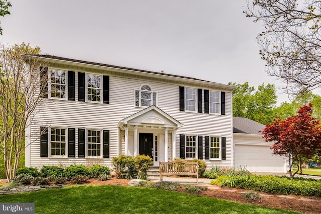 colonial house featuring a garage and a front yard