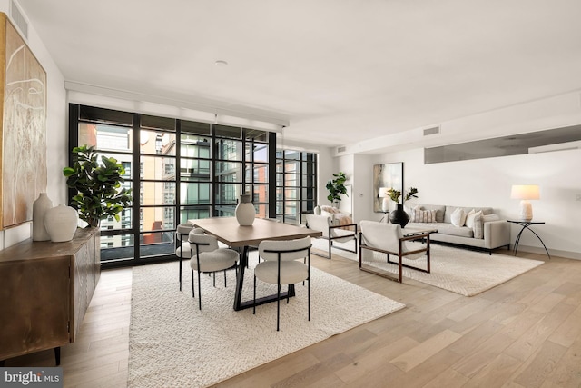 dining space with expansive windows, wood finished floors, and baseboards
