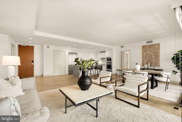 living area featuring light wood-type flooring, baseboards, and recessed lighting