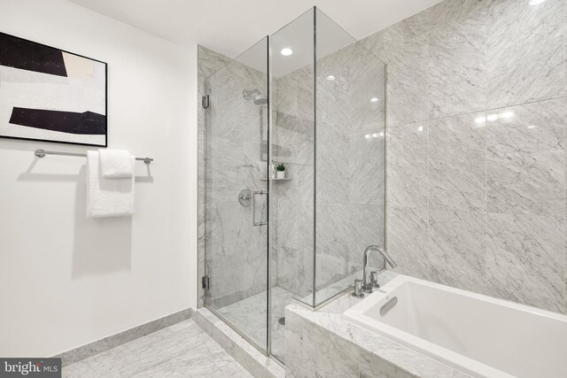 bathroom featuring baseboards, a marble finish shower, a bath, and marble look tile flooring