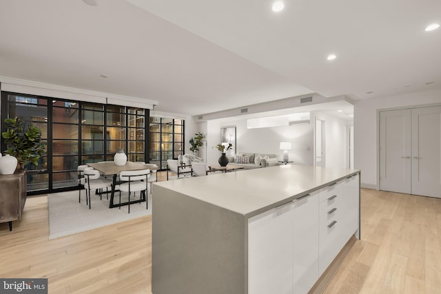 kitchen featuring white cabinetry, light wood-type flooring, modern cabinets, a kitchen island, and recessed lighting