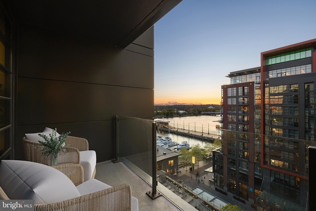 balcony at dusk with a water view and view of marina