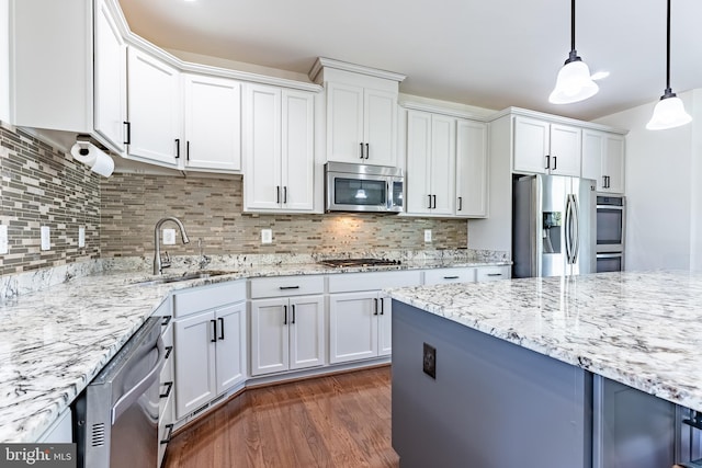 kitchen featuring appliances with stainless steel finishes, tasteful backsplash, a sink, light stone counters, and white cabinets