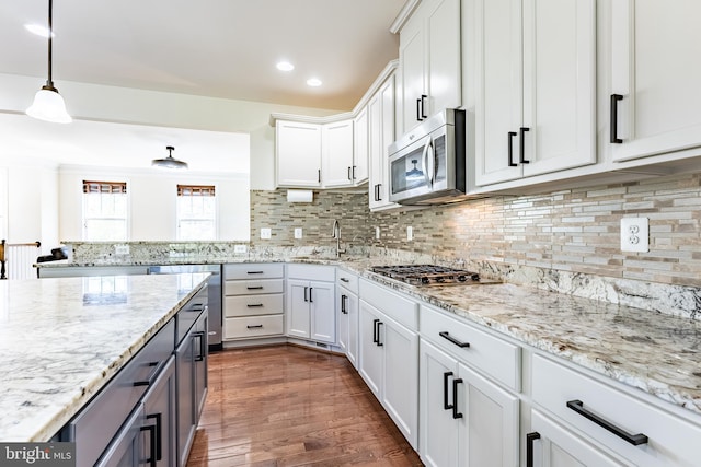 kitchen featuring a sink, appliances with stainless steel finishes, white cabinets, and light stone countertops