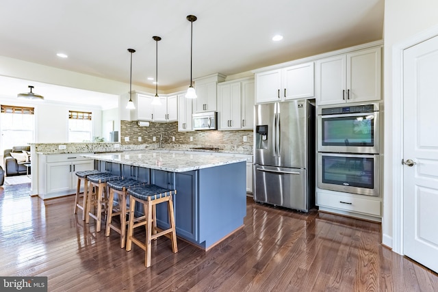 kitchen featuring decorative backsplash, dark wood-style flooring, light stone countertops, stainless steel appliances, and white cabinetry